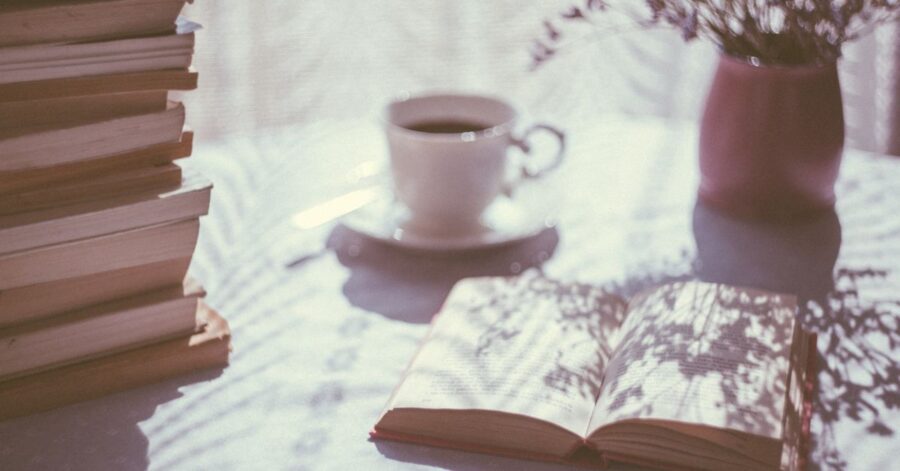 A table with many books and a cup of coffee.