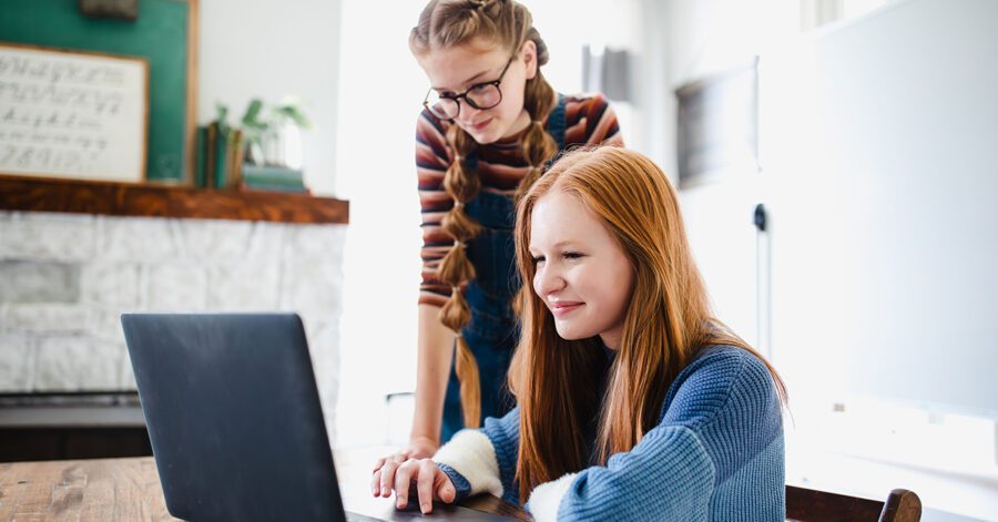 Two homeschool students researching on the computer online.