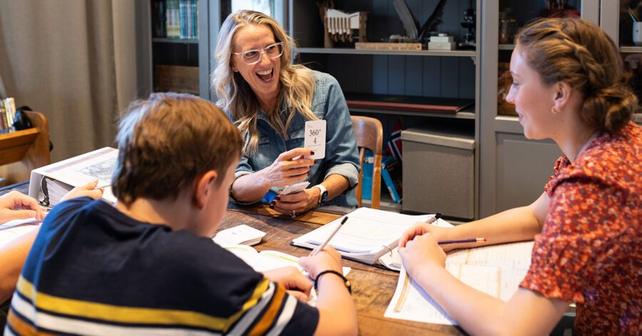 Homeschool family at a table and mom is using flashcards to review a math concept