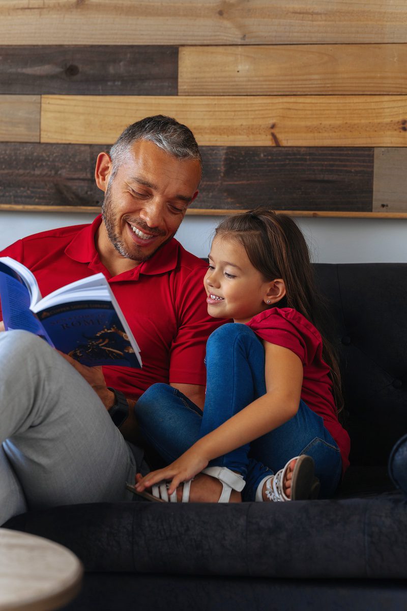 A homeschool dad reading to his daughter