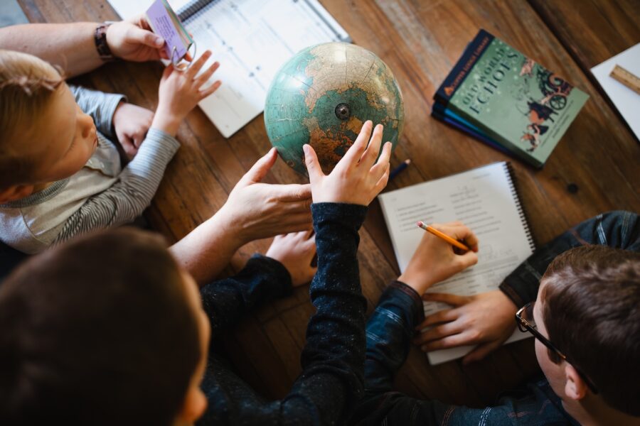 Overhead shot of a homeschool family pointing out locations on a globe