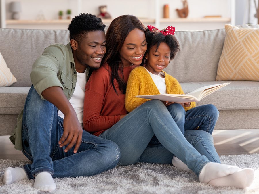 Two homeschool parents read aloud a book with their daughter
