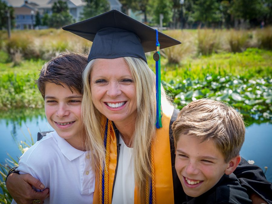 a homeschool mom graduating with her master's degree, hugging her two boys