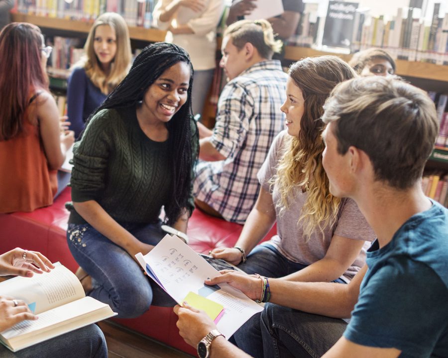 students in a library discuss what they are reading