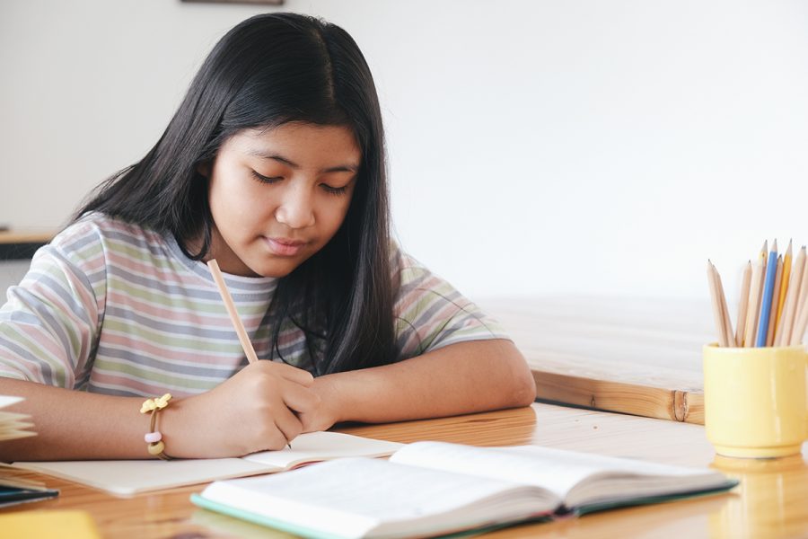 a Challenge I student writes in a notebook