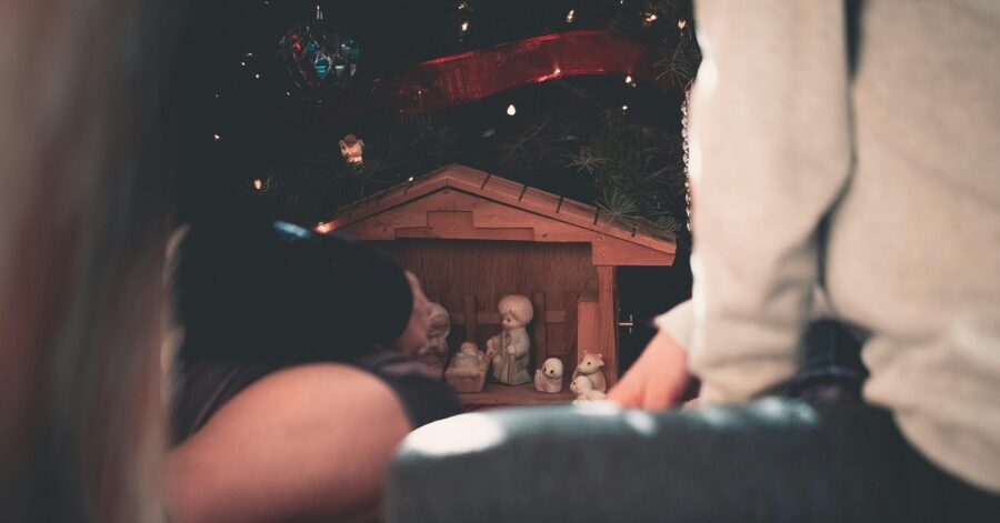 Children sit by the nativity scene.
