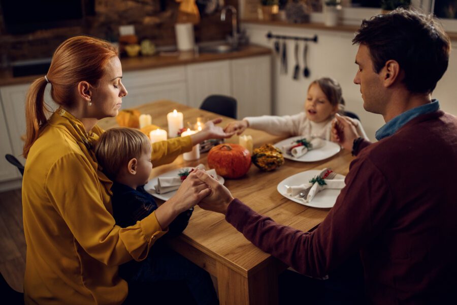 A family gives thanks to God before a Thanksgiving dinner.
