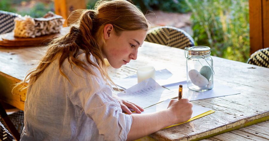 Homeschool student working on a research paper at the table.
