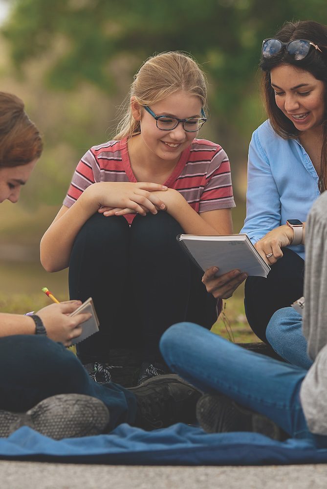 a homeschool mom pointing at a notebook explaining to her student
