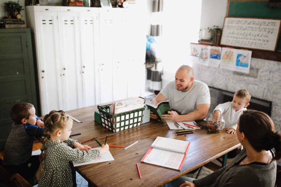 A dad homeschooling his kids at a table