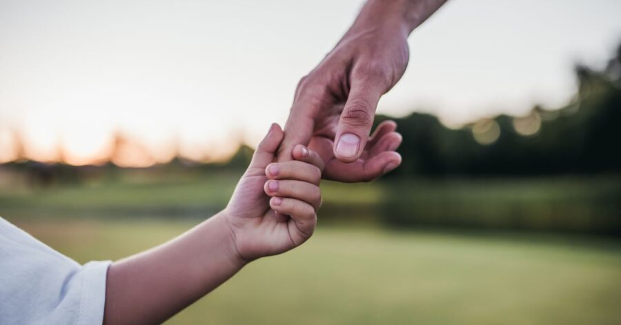 A son holds his dad's hand.