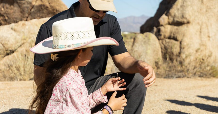 Father and girl with a cowboy hat and pink shirt using the 5 Core Habits of Grammar to Observe a plant