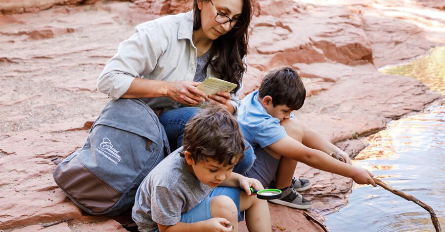 A mom and her boys attending to investigating a stream